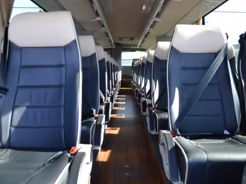 Minibus interior with leather seats, seat belts and a wood-floor aisle
